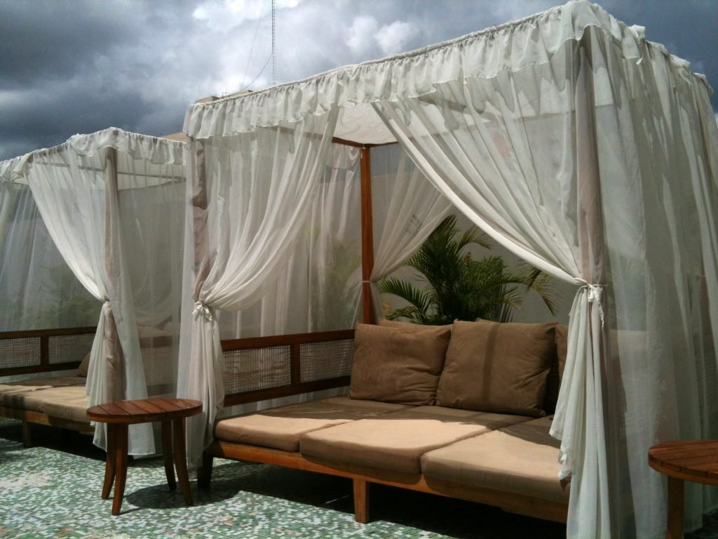 Outdoor curtains surround an outdoor couch to create privacy. 