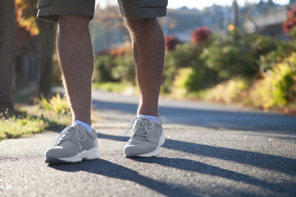 A man walks on a road wearing Propét Stability X shoes. 