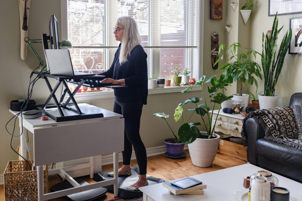 A woman works at a standing desk in her home while working from home.