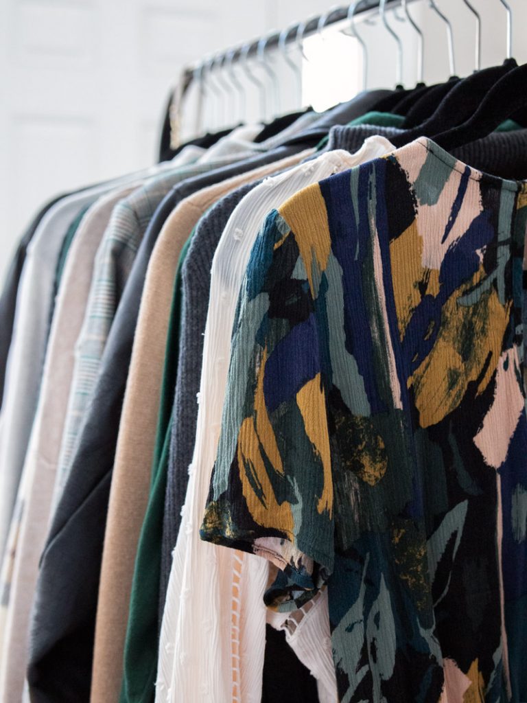 Clothes hang on a rack as part of a capsule wardrobe. 