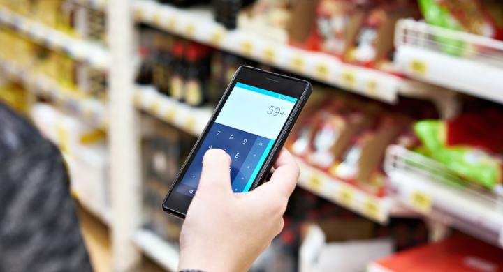 Shopper using calculator on smartphone in supermarket