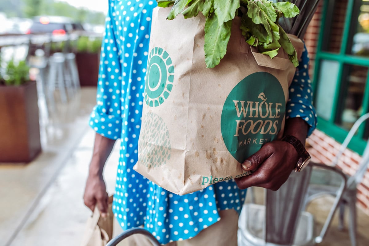 A man carries Whole Foods bags.