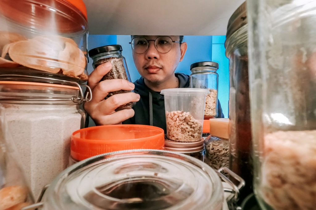 A man takes food out of his pantry to cook with. 