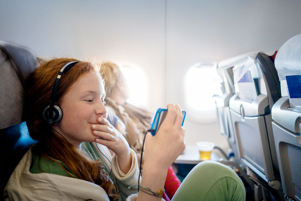 A young girl watches a movie on her iPhone on a plane.