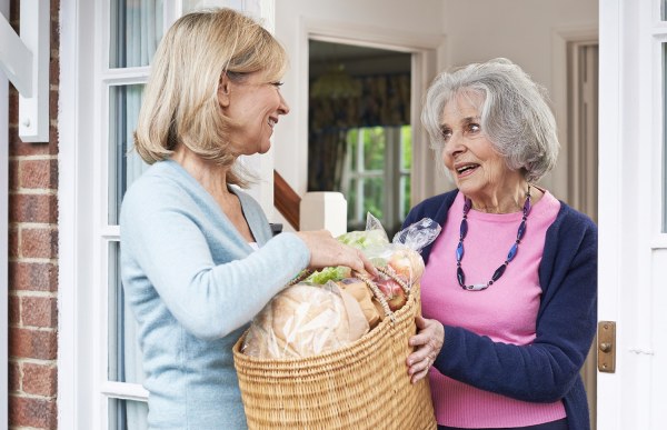 Woman giving gift basket to elderly neighbour