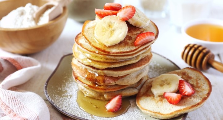 Stack of gluten free pancakes with banana and strawberry slices