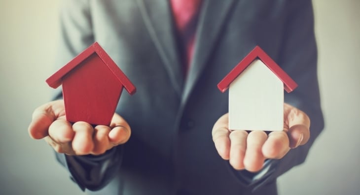 Business man holding two house models in different colours