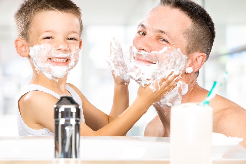 Father and son with shaving foam on their faces