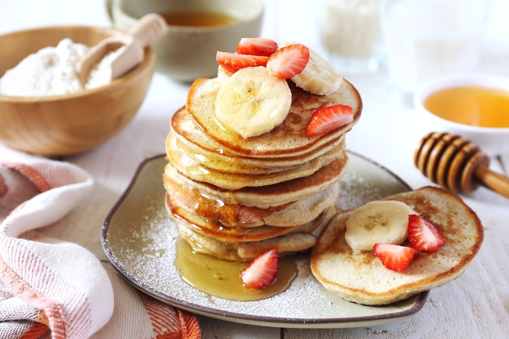 Stack of gluten free pancakes with banana and strawberry slices